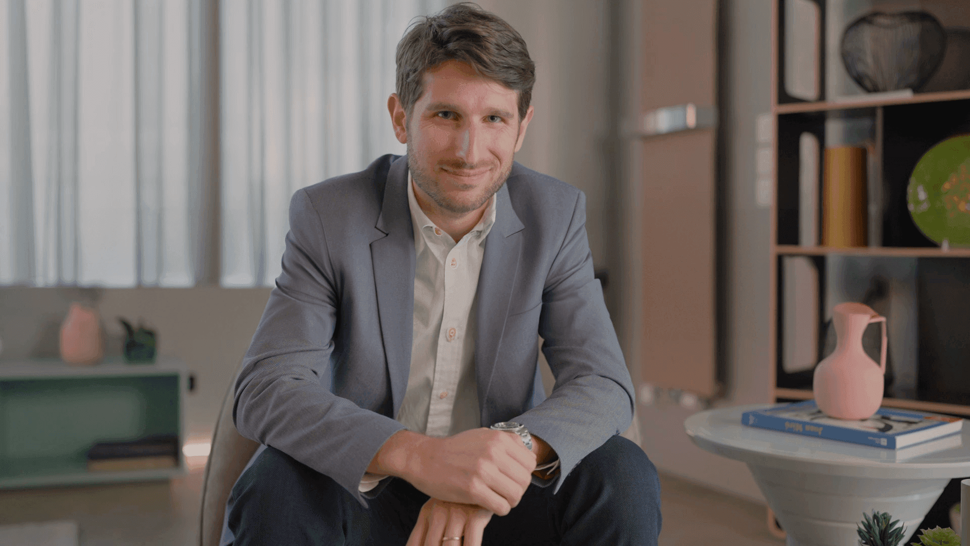 A man sitting at the center of a studio smiles at the camera. Caffeina for Samsung.